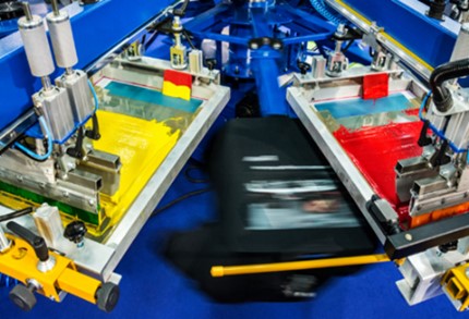 Multi-screen, screen printing press in use.