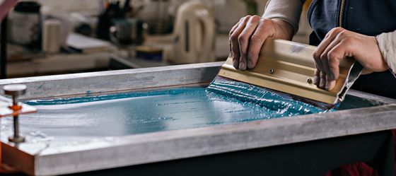 As part of the screen printing process, plastisol ink is spread  down a screen.